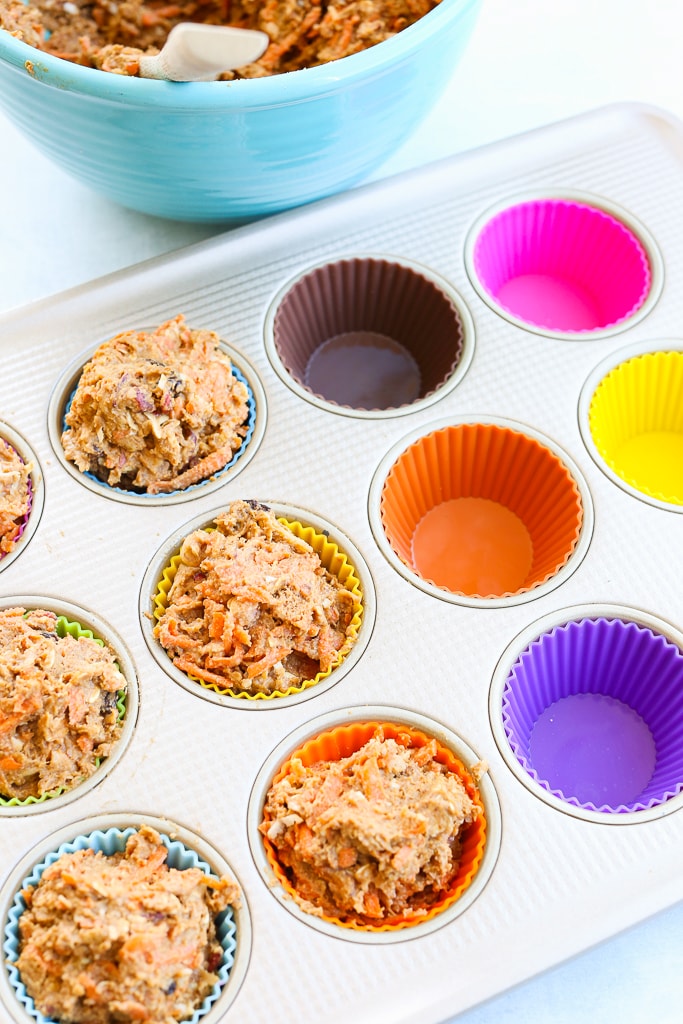 putting the batter for morning glory muffins in the silicone muffin cups half are filled half are empty