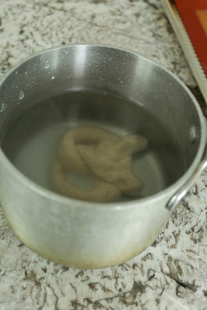 raw pretzel dough in a pan of water