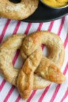 a close up overhead picture of a soft pretzel on a white and pink striped towel