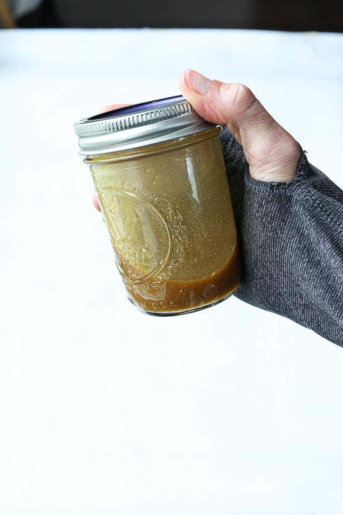 salad dressing in a glass mason jar a hand holding it