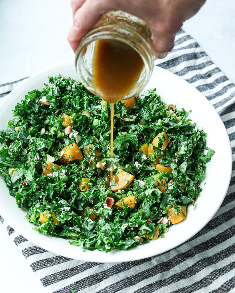 drizzling the salad dressing on the salad 