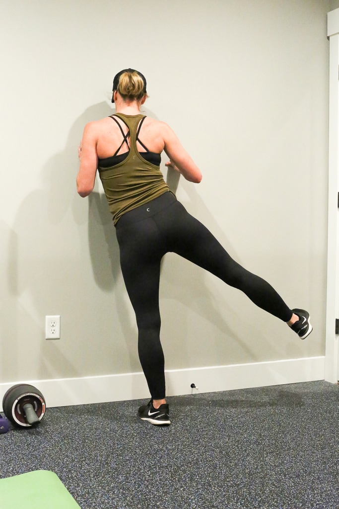 a woman against the wall completing leg lifts