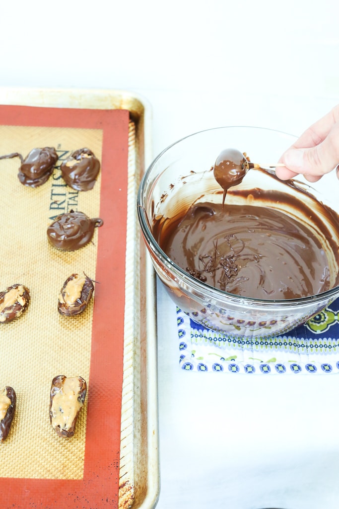 dipping a peanut butter stuffed date in chocolate with a toothpick