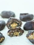 Chocolate Covered Peanut Butter Stuffed Dates cut in half and stacked on top of each other showing the peanut butter in the middle