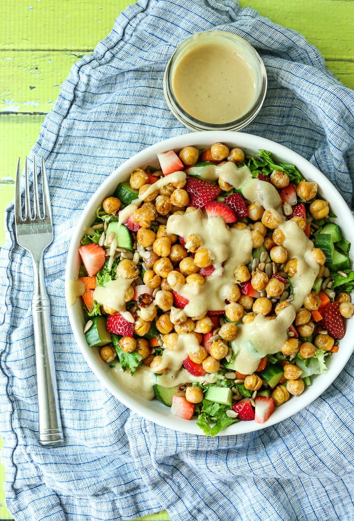 an overhead shot of a salad with lettuce, strawberry, cucumbers, and creamy vegan salad dressing on top