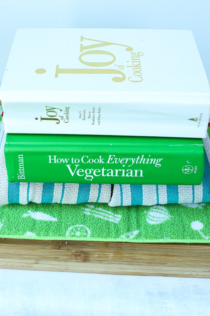 showing how to press tofu--a cutting board, with a mat, with towel-wrapped tofu, and two heavy cookbooks on top