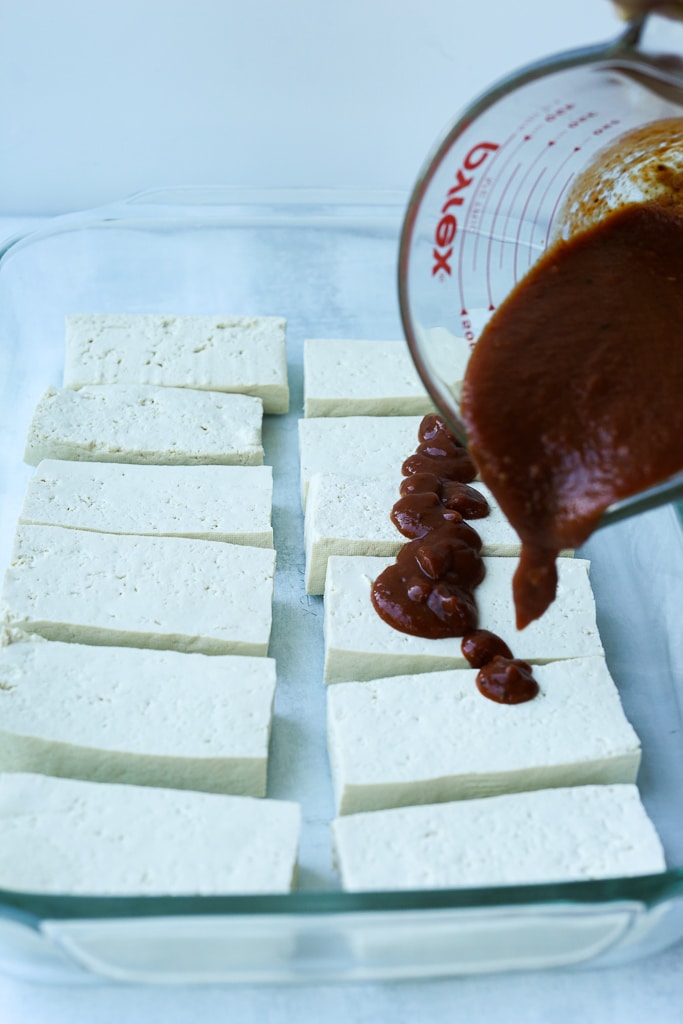 adding barbecue sauce to tofu pieces