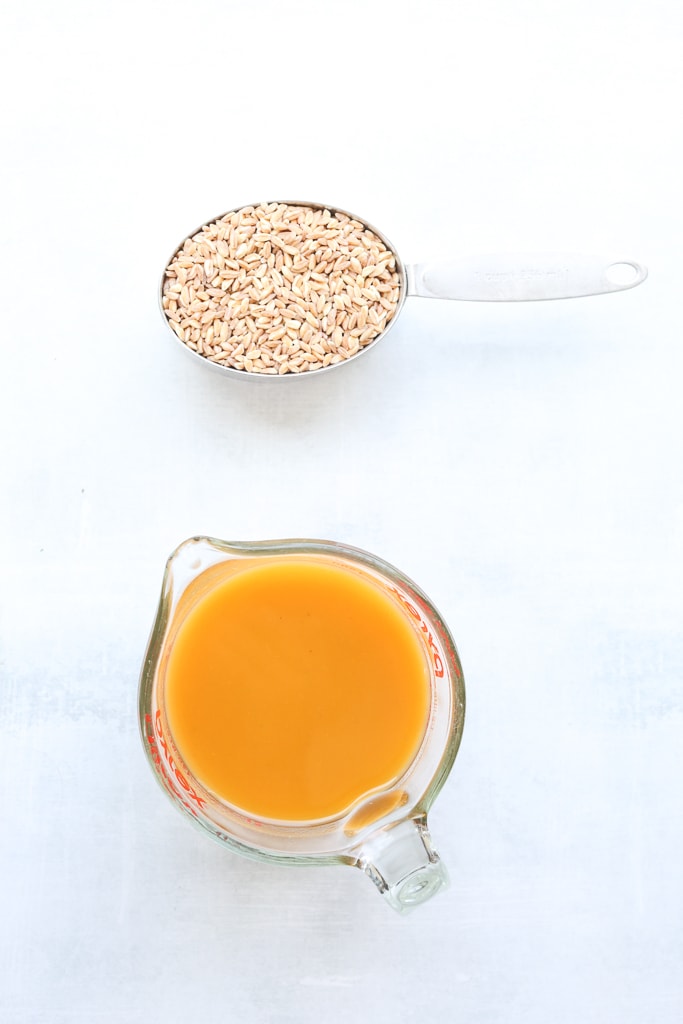 farro and vegetable broth in a measuring cup