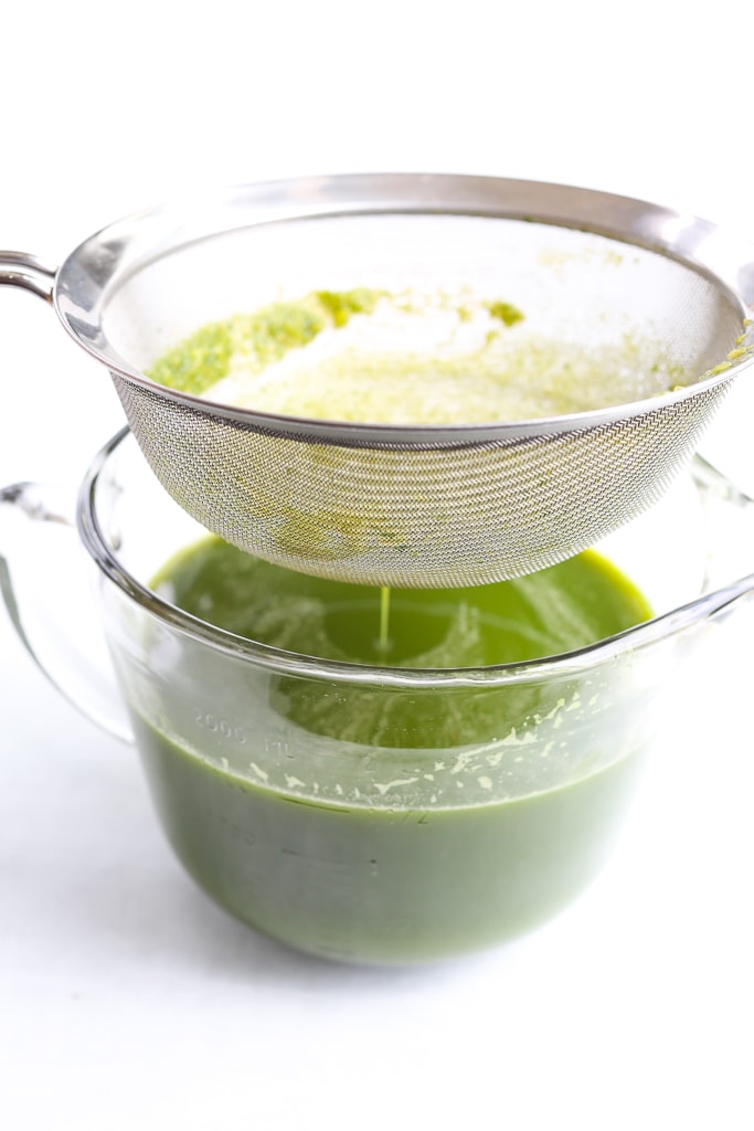 a fine mesh sieve straining fresh green juice