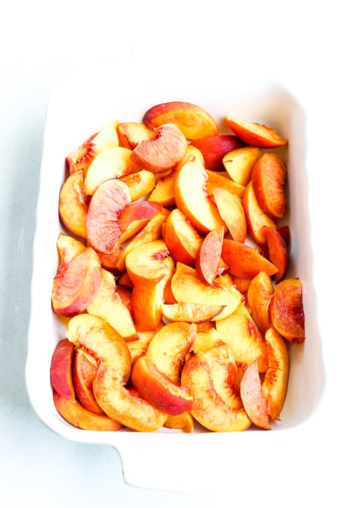 fresh sliced peaches in a white baking dish