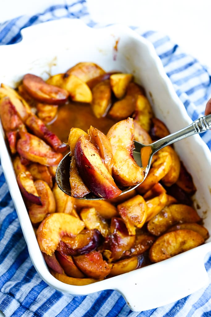 a pan of baked peaches on s serving spoon