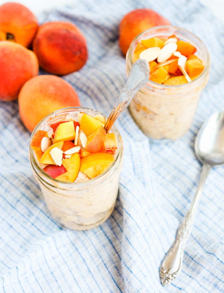a side shot of overnight oats in two jars topped with peaches 