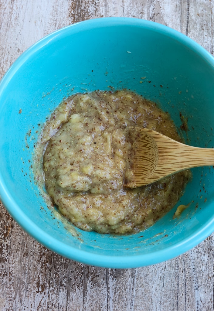 a turquoise bowl with wet ingredients and a wooden spoon