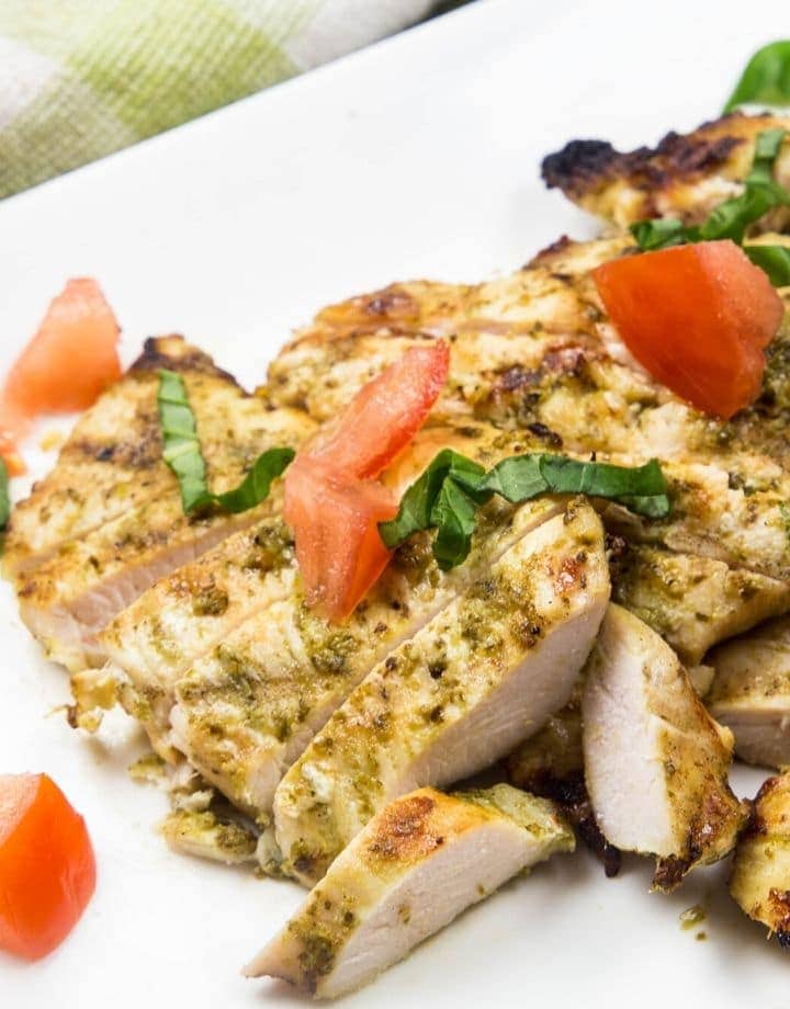 a plate of chicken with basil and tomatoes on top