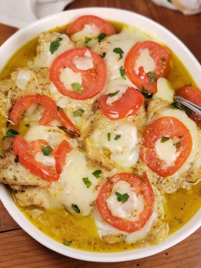 an overhead shot of cheesy tomatoes and chicken in a white bowl