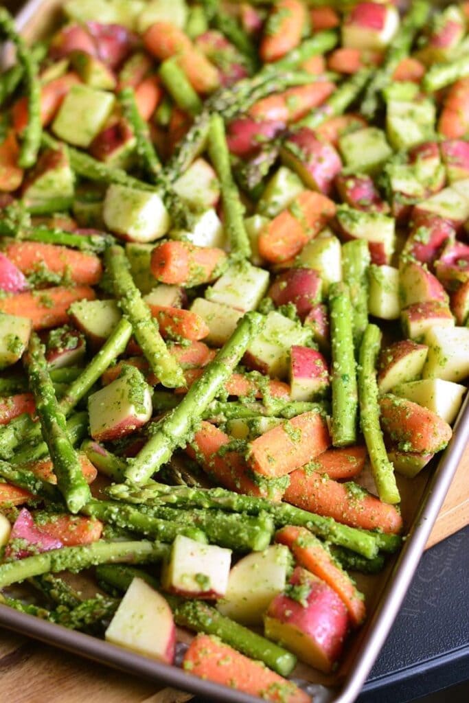 overhead shot of a try of vegetables covered in green pesto sauce