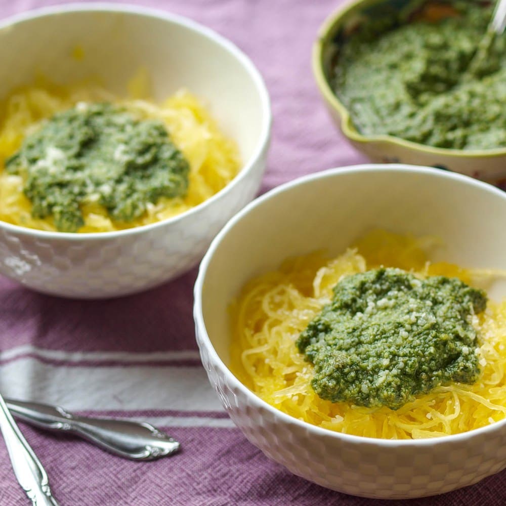 two bowls of spaghetti squash topped with green pesto sauce