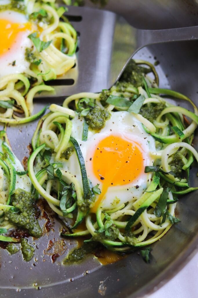 a nest of zucchini noodles in a pan with an egg in the middle