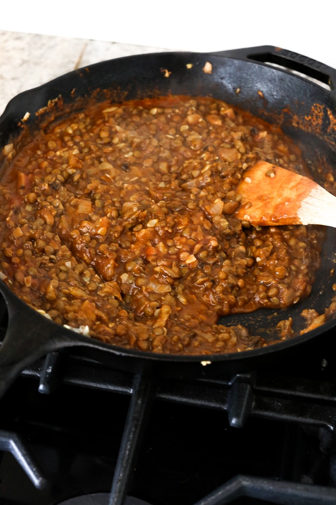lentil taco mixture cooking in a pan and a wooden spoon