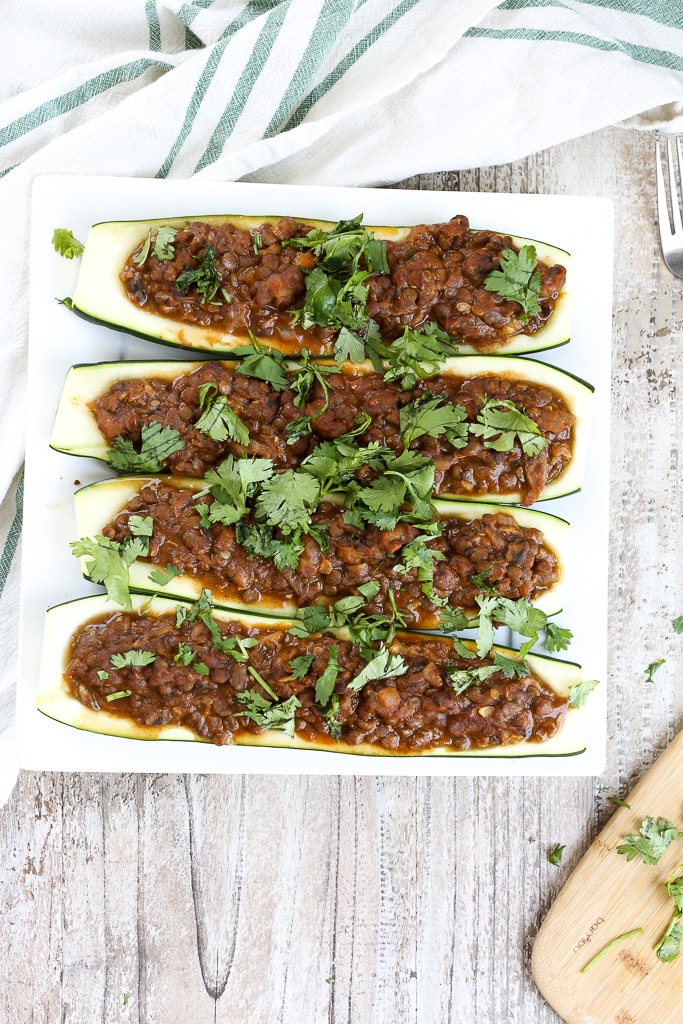 an overhead shot of taco stuffed zucchini boats topped with cilantro on a white plate