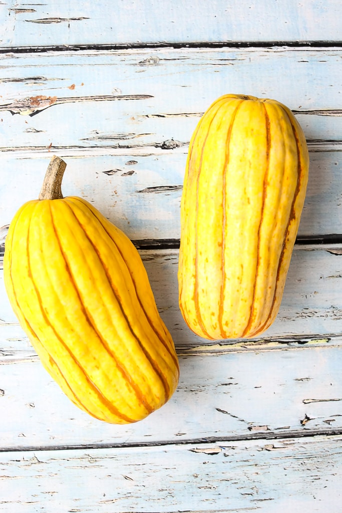 two whole Delicata squash on a board