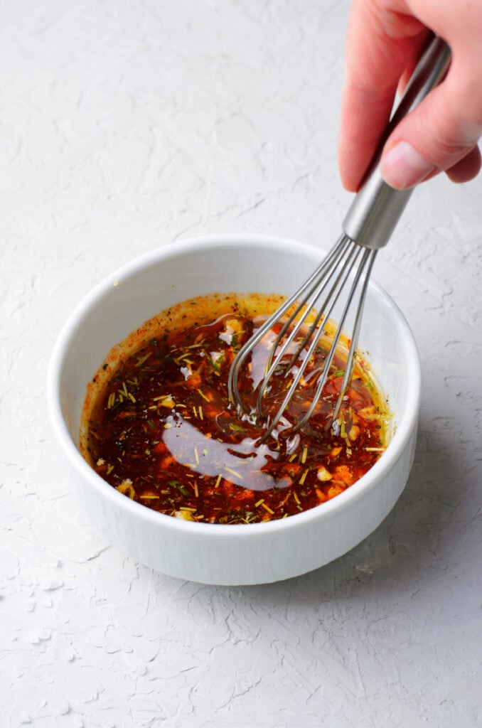 a small white bowl with marinade being whisked