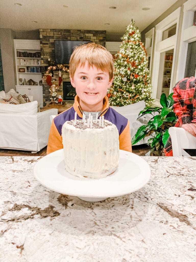 Luke with a big smile and birthday cake with candles in front on him