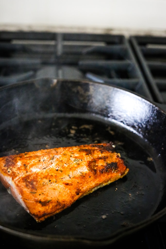 a filet of salmon in a skillet with browned top