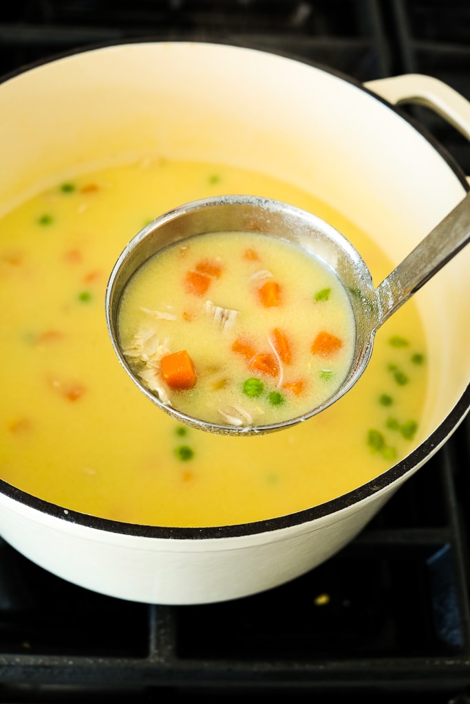 A pot of Greek Lemon CHicken Soup with a ladle taking a scoop out