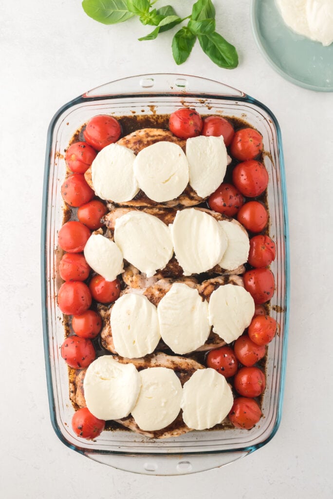 a pan of caprese chicken with mozzarella on top