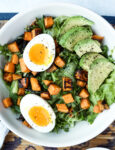 close up photo of breakfast salad with soft boiled egg, avocado and sweet potato