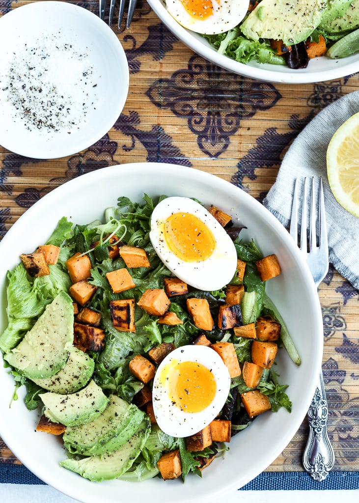 a plate of breakfast salad with fork and a lemon half