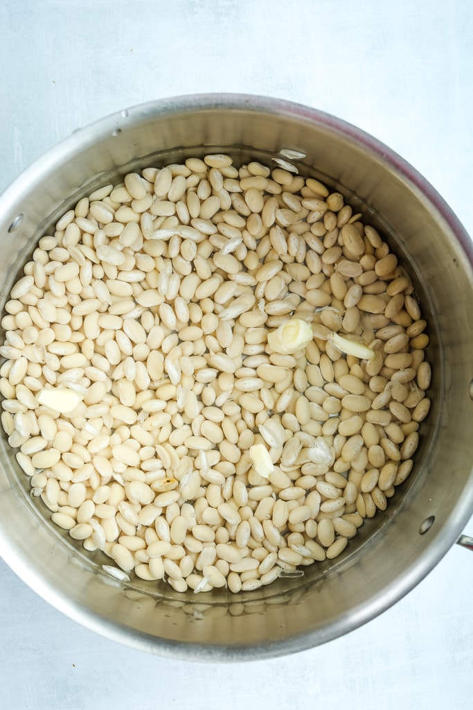dry white beans in a large pot with whole garlic cloves