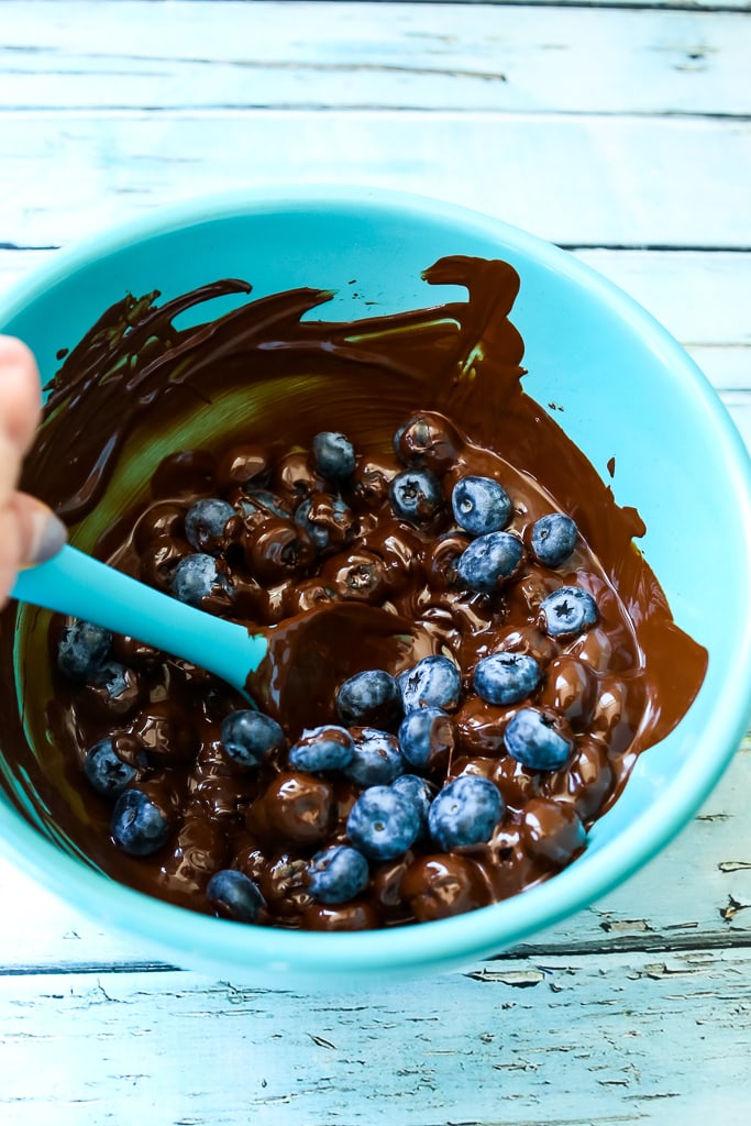 stirring fresh blueberries into melted chocolate