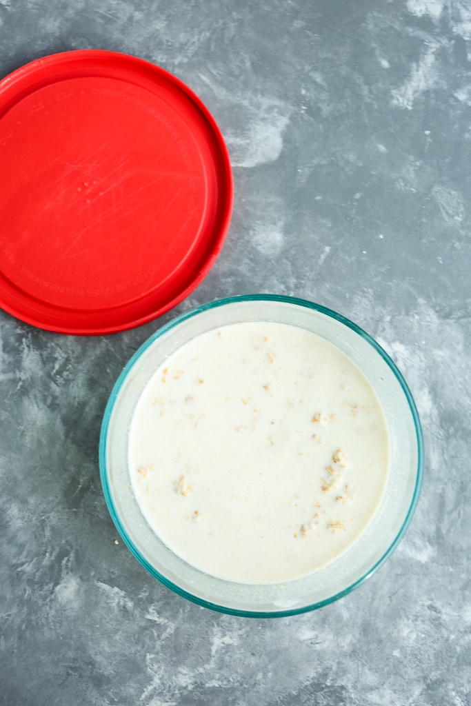 mixed ingredients in glass container with a red lid next to it.