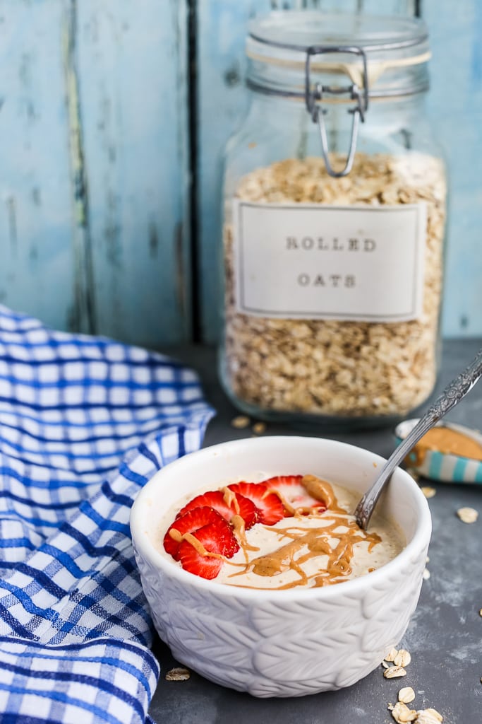 a bowl of peanut butter overnight oats with a jar of old fashioned rolled oats in the background