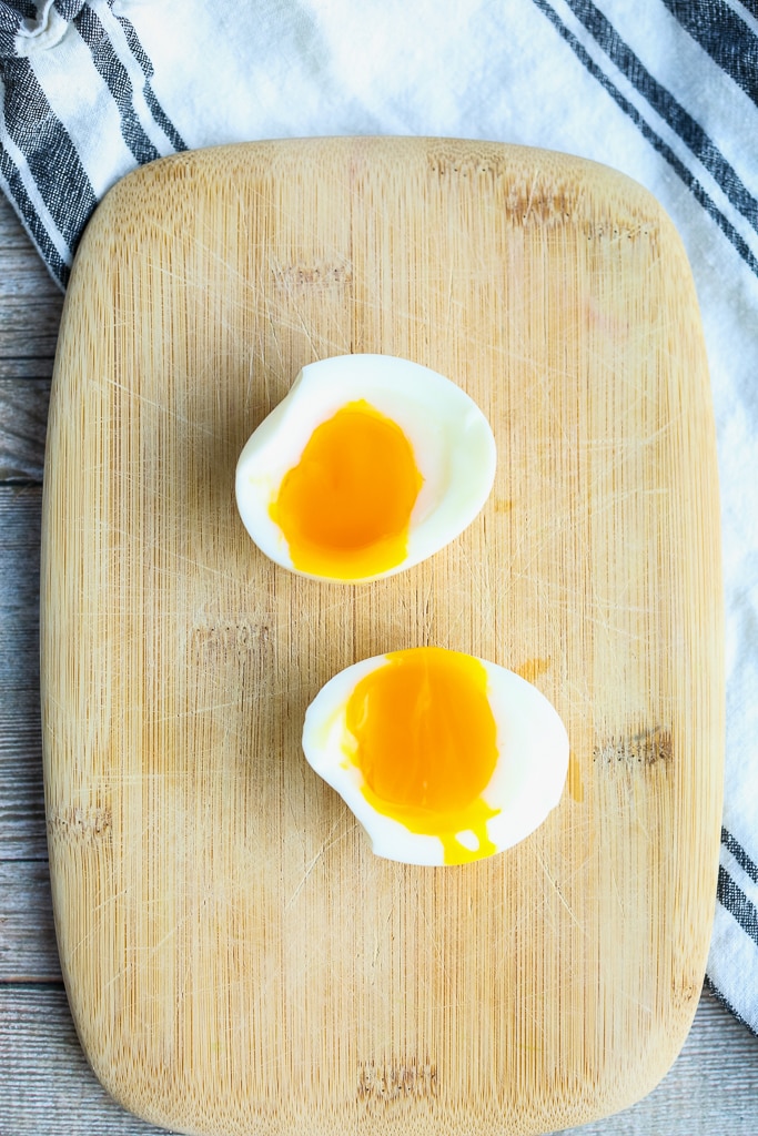 two soft boiled eggs on a wooden cutting board