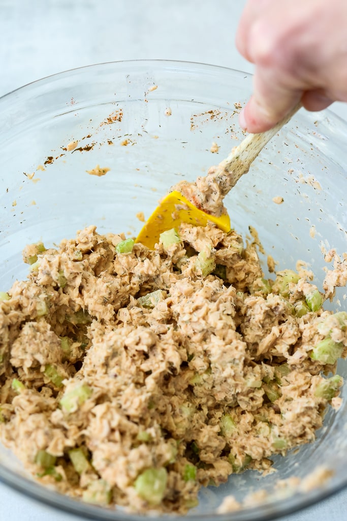 stirring salmon with the rest of the ingredients in a glass bowl