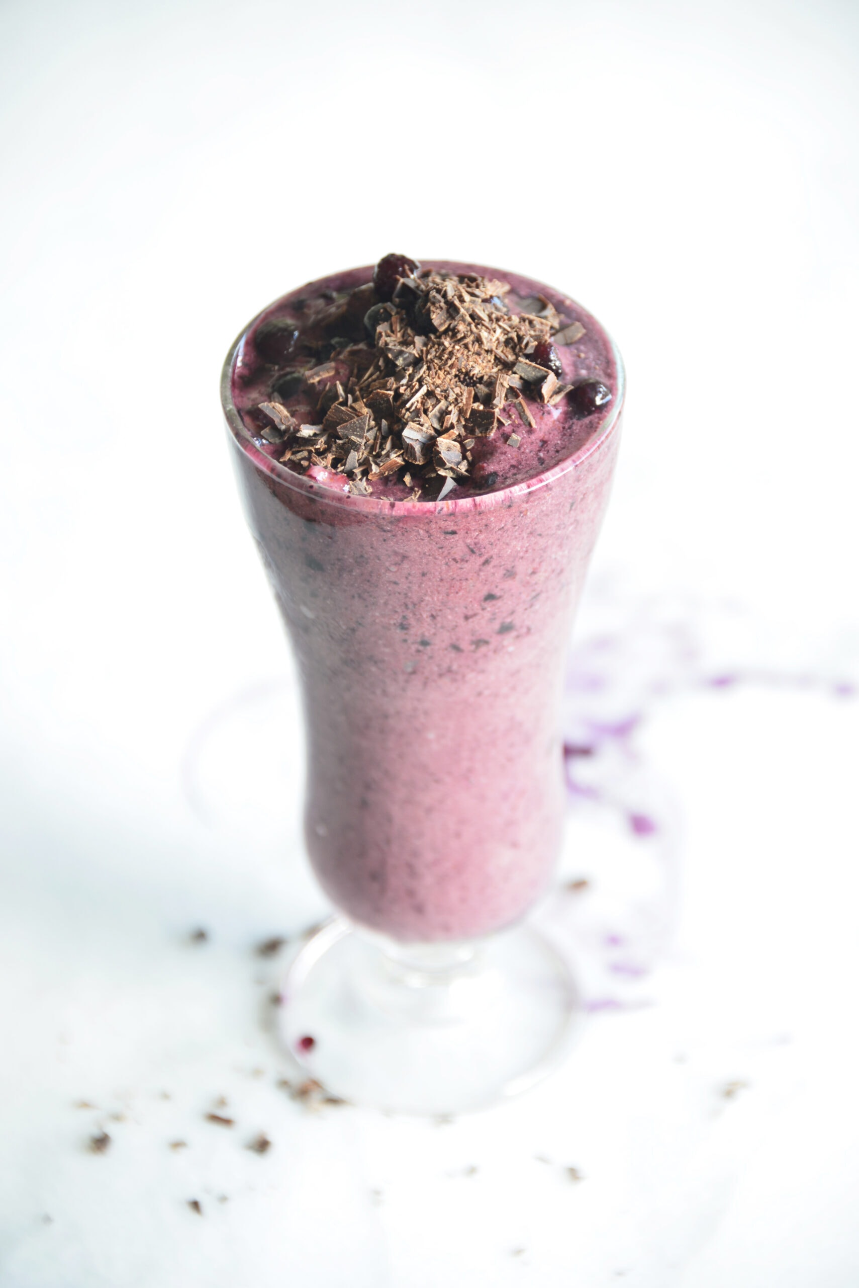 blueberry chocolate smoothie in a tall glass with chocolate and blueberries on top