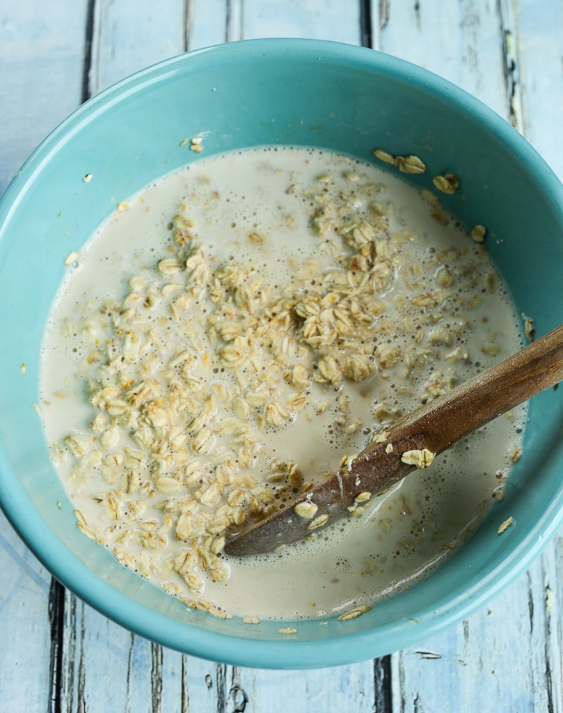 milk and oats in a bowl being stirred together with a wooden spoon