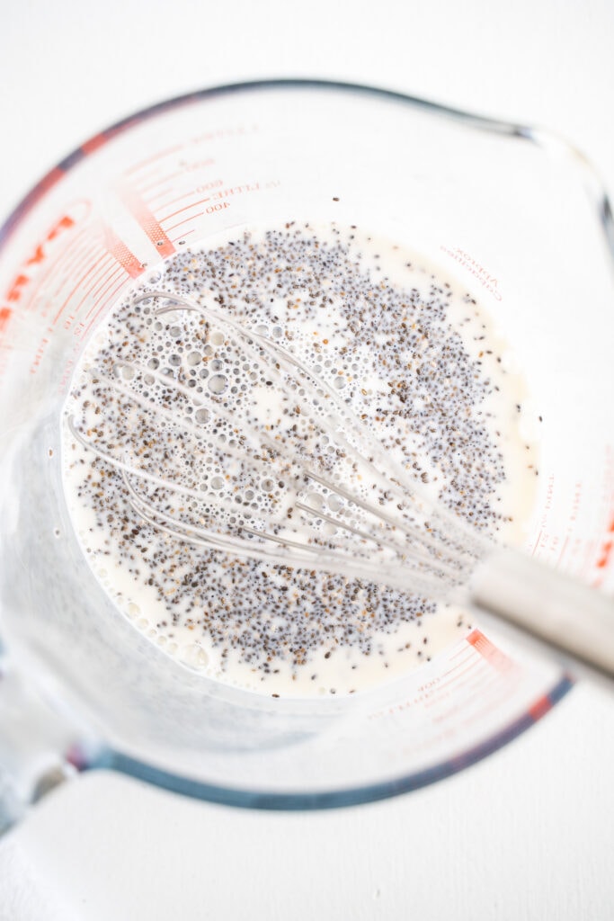 whisking together chia seeds and milk in a glass measuring cup