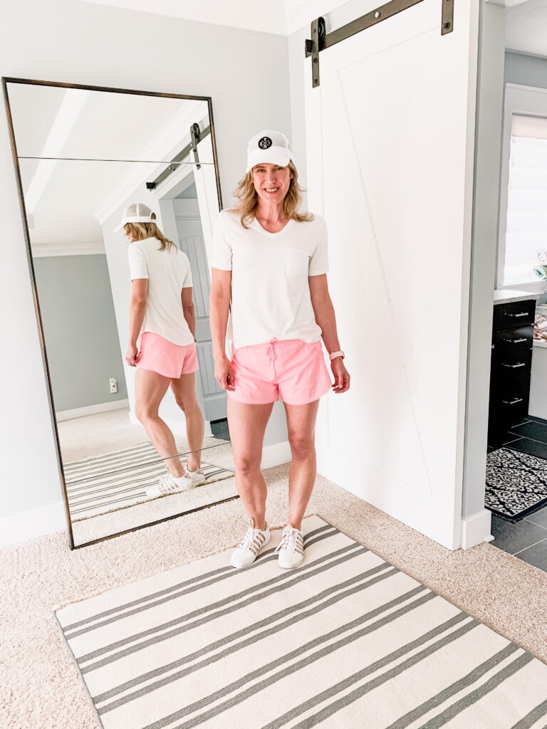 woman in pink shorts and white tee shirt with a hat on