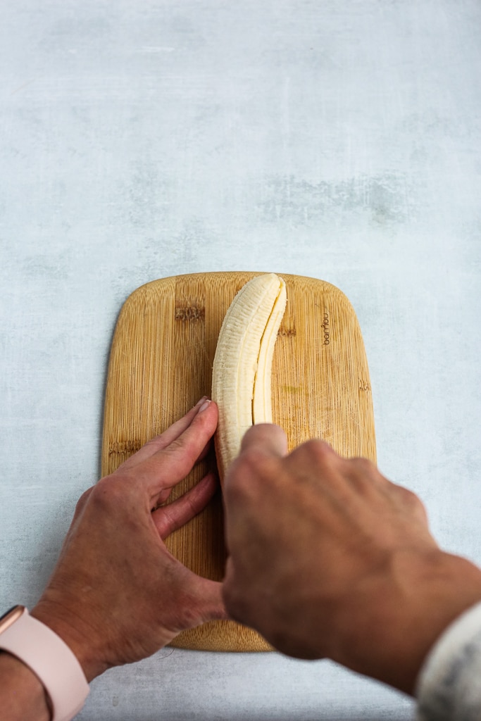 slicing a banana in half on a cutting board