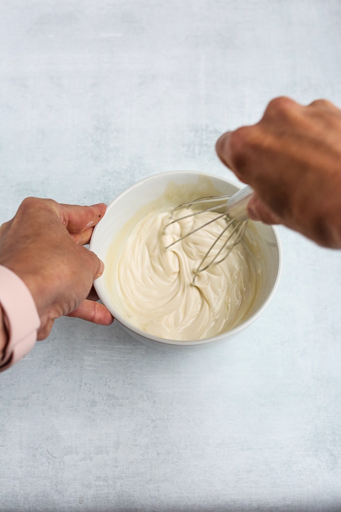 whisking yogurt in a white bowl
