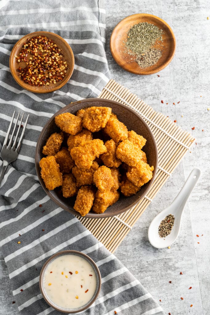 vegan chicken nuggets on a table with sauce next to it