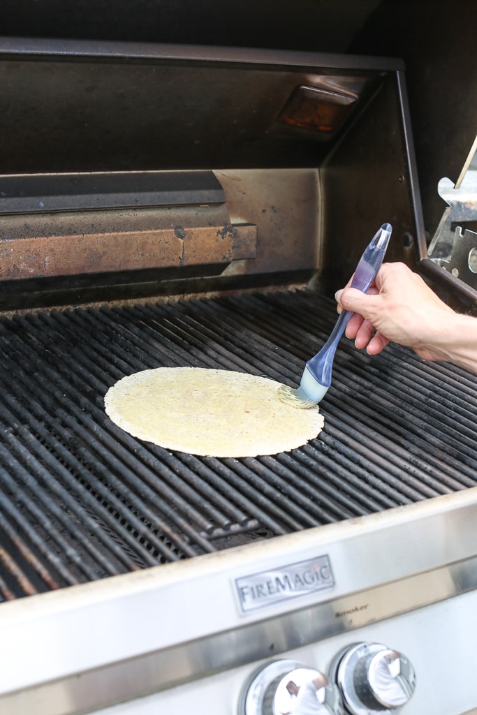 spreading mustard on a tortilla on the grill