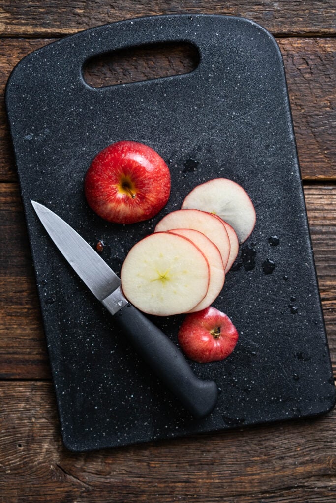 apple slices on a black cutting board with a knife