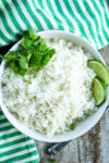 a white bowl of coconut rice recipe with cilantro and lime