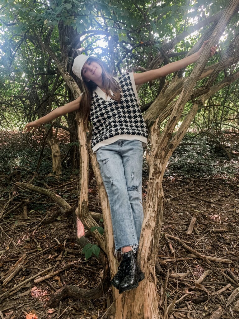 a young girl in the woods leaning against a tree