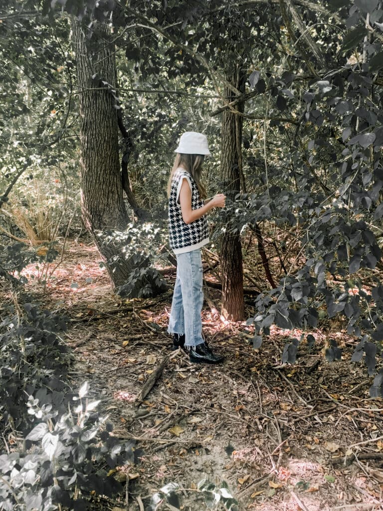 a young girl in the woods with her back to the camera